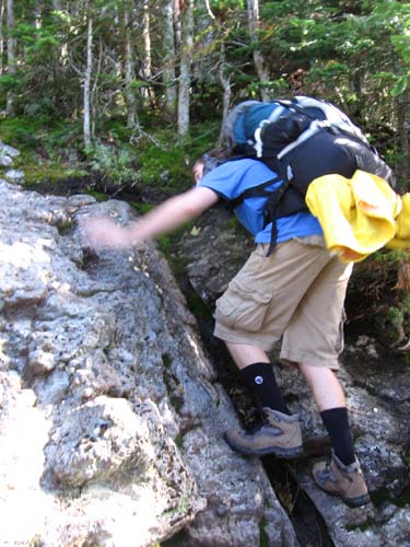 backpacker scrambling up ledge