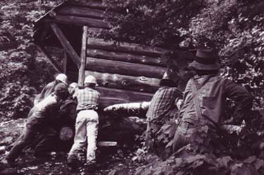 people using log to lever up log cabin